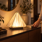 Pyramid ambient lamp on a console beside a person's hand and book