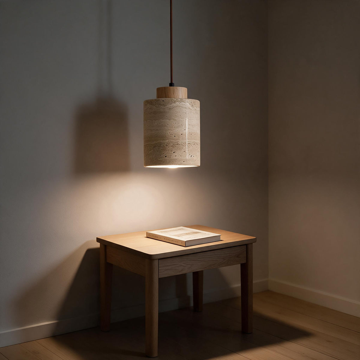 The travertine pendant light hanging on its cord above a small dining table.
