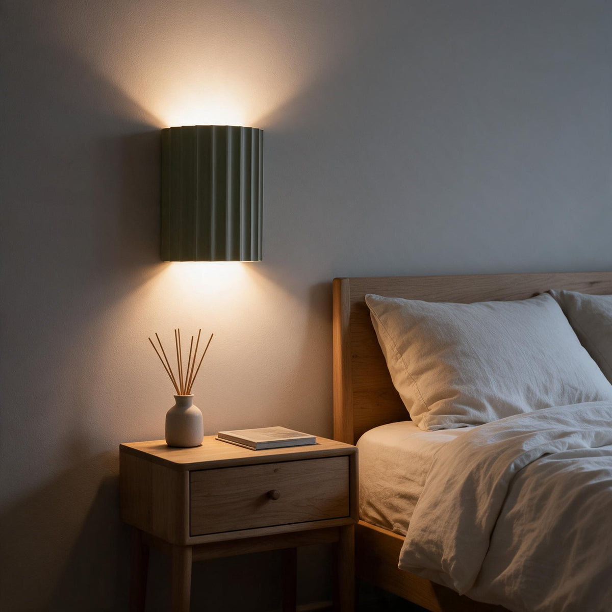 The resin wall lamp mounted above a bed, casting light upward and downward along the wall.
