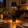 Black USB rechargeable bottle lamp glowing on a dining table