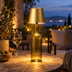 Golden USB rechargeable bottle lamp glowing on an outdoor patio table